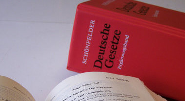 Das Bild zeigt den Rücken eines Gesetzbuchs, davor liegt ein aufgeschlagenes Gesetzbuch. (Quelle: Freelancer0111 / pixelio.de)