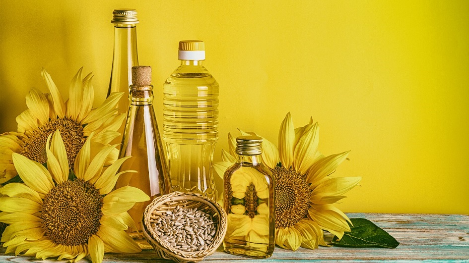 Das Bild zeigt mehrere Flaschen Sonnenblumenöl vor gelben Hintergrund.