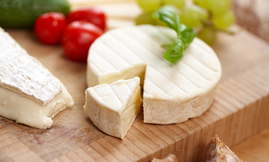 Das Bild zeigt einen Käse auf einem Holzbrett.