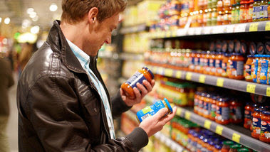 Das Bild zeigt einen Mann im Supermarkt, der zwei Gläser mit Fertigsossen in den Händen hält und die Etiketten liest. (Quelle: Marcus Gloger / BVL)