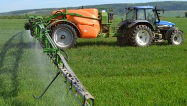 Das Bild zeigt ein landwirtschaftliches Fahrzeug beim Spritzen von Pflanzenschutzmitteln auf dem Feld. (Quelle: Dittmar / SVLFG)